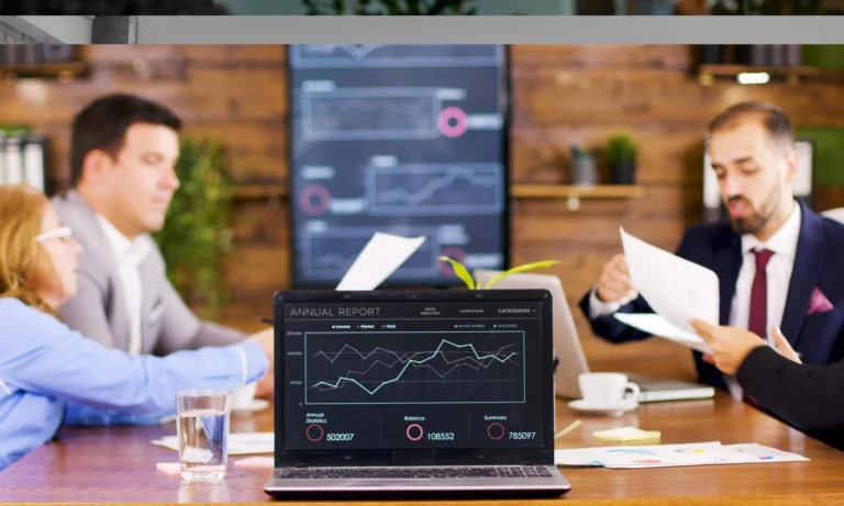 On the table laptop showing charts in the conference room. Business people having an i